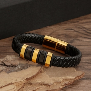 Detail of black braided leather bracelet with gold magnetic clasp on wooden bark texture