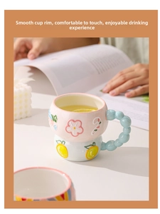 Close-up of pink embossed ceramic mug with 3D floral details and beaded handle