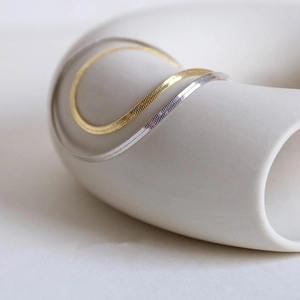 Minimalist gold and silver snake bone chain necklaces displayed on white sculpture