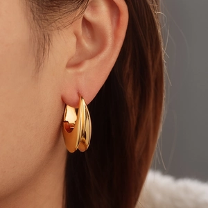 Polished gold titanium steel U-shaped hoop earrings worn by a female model