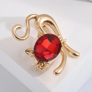 Detailed close-up of golden cat brooch with large oval red crystal and polished metal finish