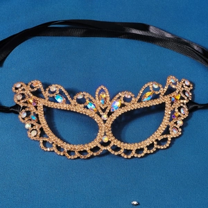 Close-up of luxury gold masquerade mask with colorful rhinestones and black satin ties
