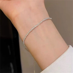Minimalist silver chain bracelet shown on a woman wrist with sparkling metallic finish