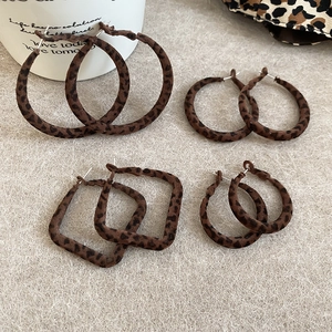 Détail de boucles d'oreilles géométriques floquées à motif léopard rétro marron et noir