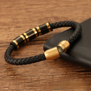 Detail view of black woven leather bracelet with gold magnetic clasp on wooden background