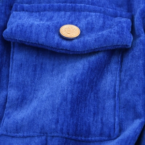Macro di un abito in ciniglia blu reale con dettaglio tasca e bottone dorato goffrato