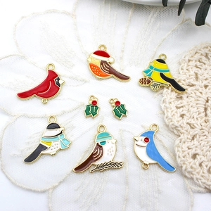 Detailed macro view of colorful enamel bird charms and holly leaf pendants for DIY jewelry