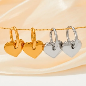 Goldene und silberne 3D Herz-Creolen auf einem eleganten Seidenhintergrund