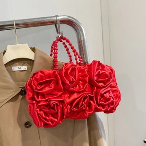 Detail of red satin evening bag with 3D rose flower design and beaded strap on trench coat