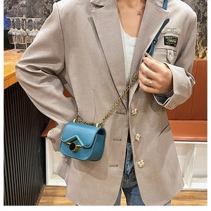 Dettaglio di una mini borsa a tracolla turchese con chiusura a V dorata su una modella