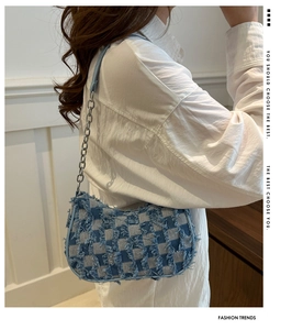 Detail of blue and white checkered denim bag featuring distressed fringe and metal chain strap