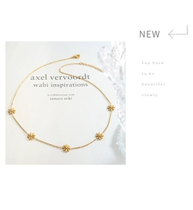 Detail of gold daisy flower necklace featuring five floral charms on a delicate chain