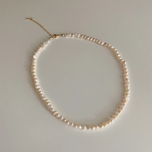 Detailed macro view of freshwater pearl necklace with golden lobster clasp and chain