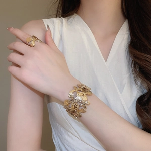 Vista dettagliata del set bracciale e anello a fiore dorato testurizzato su modella