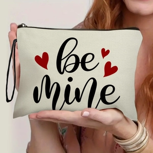 Off-white canvas makeup bag with 'be mine' text and red hearts held by hands