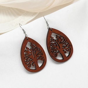 Détail de boucles d'oreilles en bois marron foncé avec gravures d'arbre de vie creuses