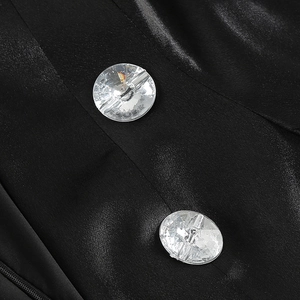 Details aus schwarzem Satinstoff mit zwei kristallgeschliffenen Zierknöpfen an der Jacke