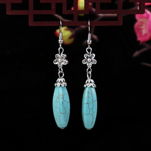 Detail of vintage turquoise drop earrings with silver flower and blue stone textures