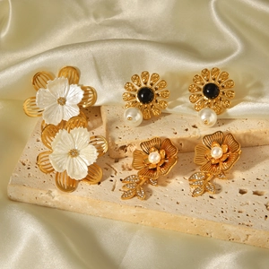 Three pairs of elegant gold flower earrings with pearls and mother of pearl on stone