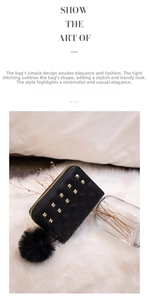 Detail of black quilted coin purse with gold studs and large faux fur pompom charm