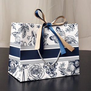 Floral gift bag with blue butterfly prints and elegant ribbon bow on dark wood surface