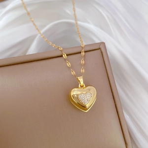 Detailed view of a gold heart pendant with pavé cubic zirconia on soft white silk