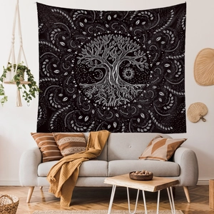 Detail of life tree tapestry with moon and sun patterns hanging above a sofa in a cozy room
