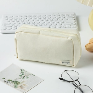 Creamy white canvas pencil case with zipper and aesthetic stationery on a desk