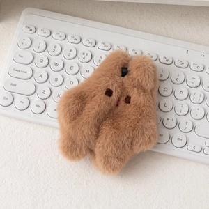 Gros plan du porte-monnaie lapin en peluche marron sur clavier montrant texture et détails