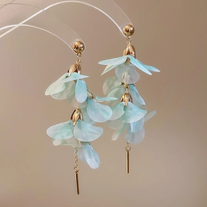 Détail de boucles d'oreilles avec pétales en acrylique bleu clair et glands dorés