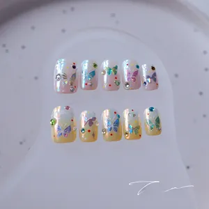 Macro detail of gradient butterfly press-on nails with colorful rhinestones and 3D charms