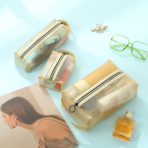 Three beige nylon mesh makeup bags with black zippers on a light blue background set