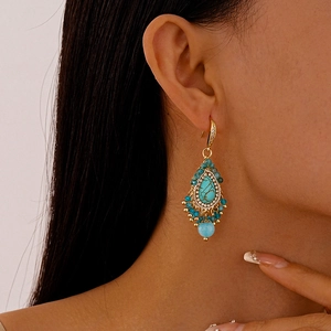 Detailed view of bohemian teardrop earrings with turquoise stones and blue beads on model