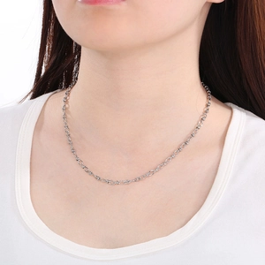 Close-up detail of a minimalist silver cross chain necklace on a female model neck
