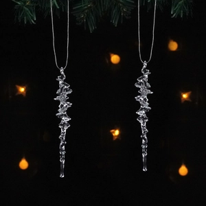 Close-up of clear icicle crystal ornaments hanging from silver chains on pine branches