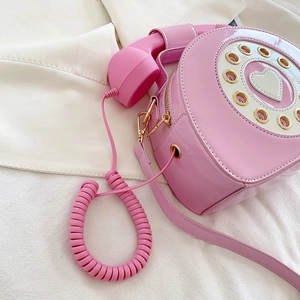 Detail of creative pink retro telephone bag featuring a heart dial and spiral strap