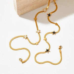 Gold-plated flat snake chain necklace with black and white star pendants on white background