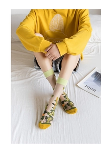 Close-up of sheer mesh crew socks with yellow floral embroidery and elastic yellow cuffs