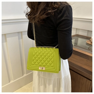 Quilted green crossbody bag with gold chain strap shown on model in stylish indoor setting