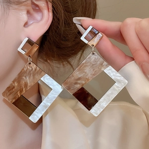 Detail of geometric acrylic pendant earrings in brown and tortoiseshell on a model