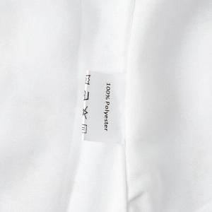Detail shot of white care label on dress showing 100% polyester fabric and washing icons