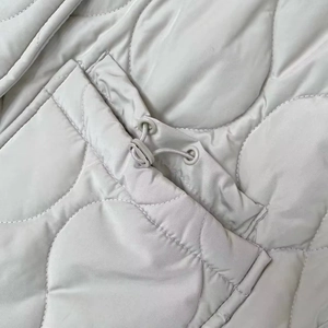 Detailed macro view of wavy quilted fabric and adjustable drawstring toggle on vest