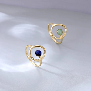 Elegantes anillos dobles de oro con lapislázuli azul y jade verde sobre fondo azul