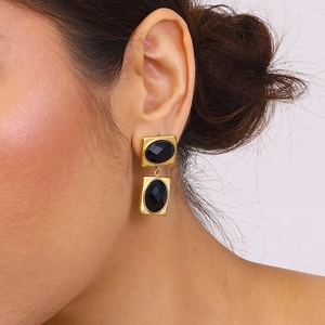 Close-up of vintage gold titanium steel earrings with faceted black gemstone drops