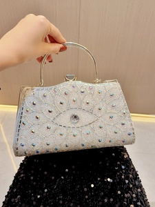 Gros plan d'un sac de soirée en strass avec motif œil grec et poignée en métal argenté