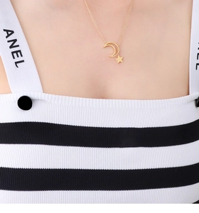 Close-up of golden moon and star pendant necklace worn on the collarbone