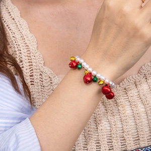 Weihnachtsperlenarmband mit bunten Glocken und Perlen am Handgelenk einer Frau