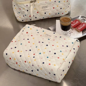 Quilted cotton makeup bag with colorful polka dots on a metal table in a cozy scene