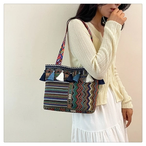 Detail of bohemian woven tote bag showing colorful wave patterns and blue tassels