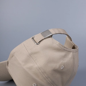 Détail de la boucle métallique réglable et de l'anneau en D sur casquette en coton beige